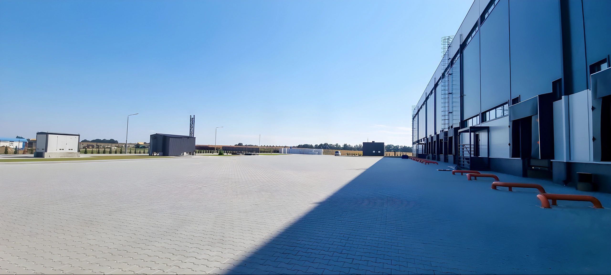 Modern industrial warehouse exterior with loading docks under clear sky